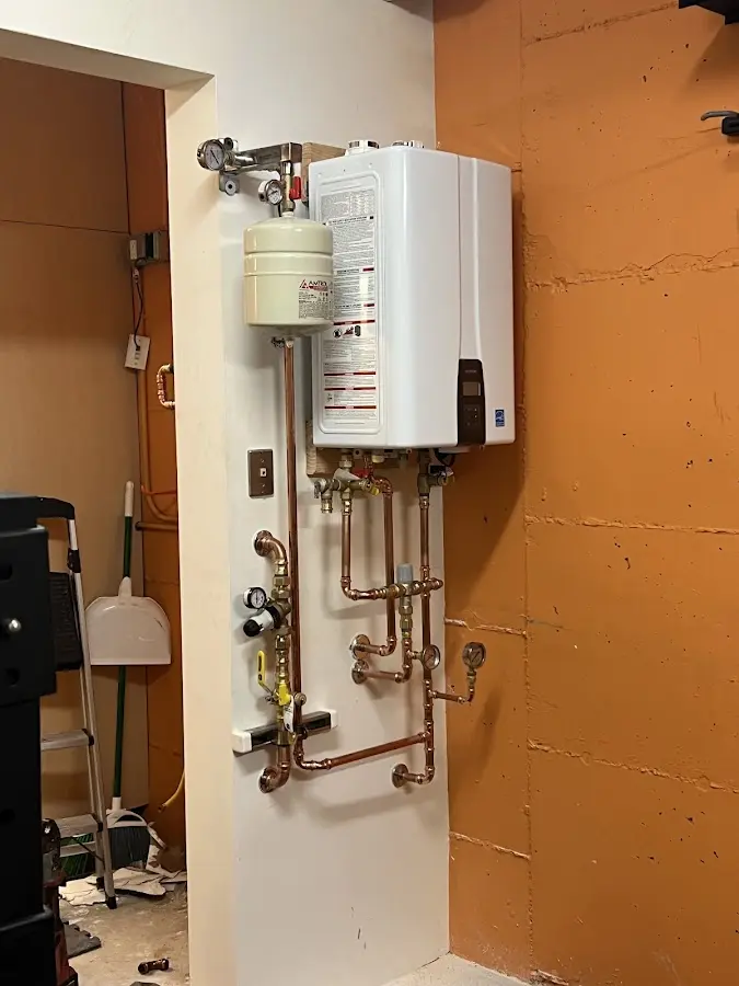 Plumbing technician inspecting water heater connections in West Deer